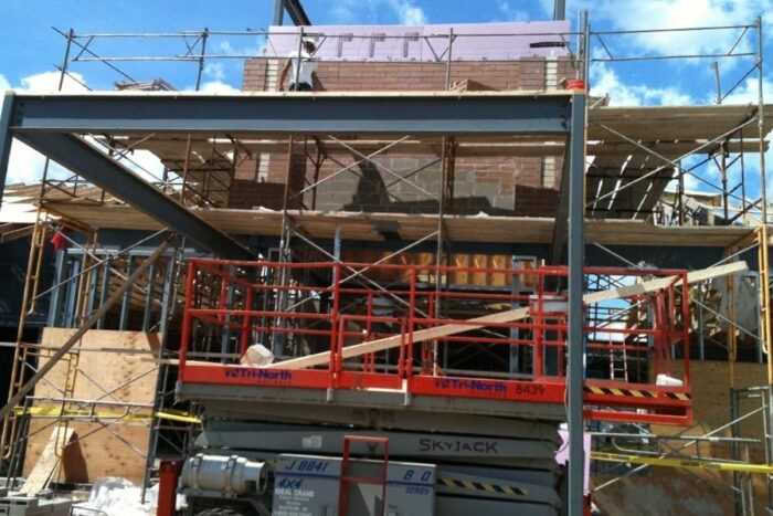 brick building being constructed with a lift machine and scaffolding